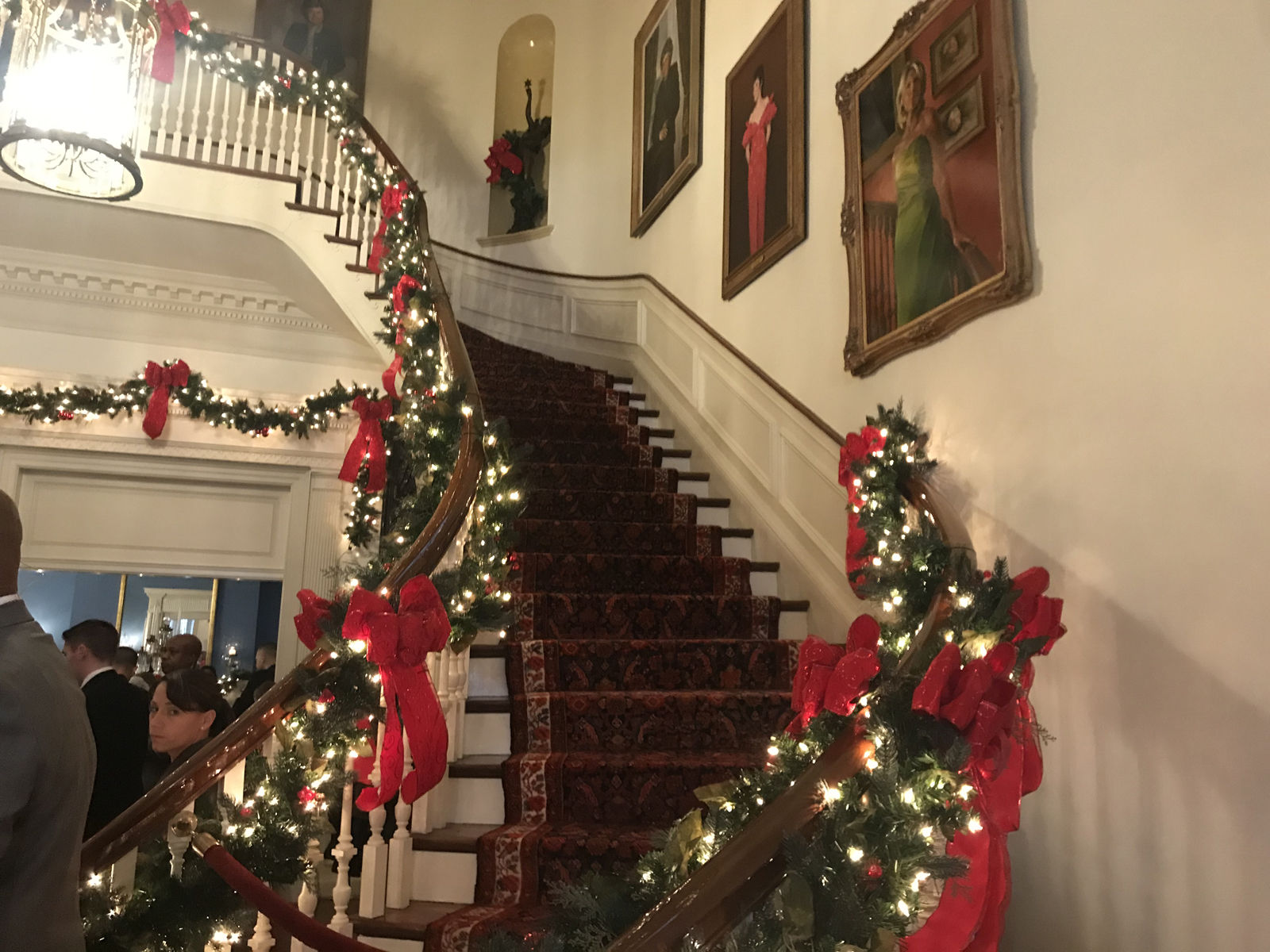 The grand entrance hall was decorated with greenery and red bows sweeping up the grand staircase. (WTOP/Dick Uliano)