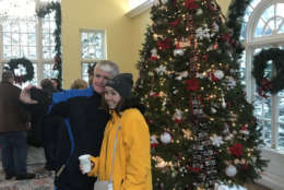 In the conservancy overlooking the gardens, visitors posed for pictures and selfies in front of another tall tree decorated with lights and red and gold ornaments of many shapes. (WTOP/Dick Uliano)