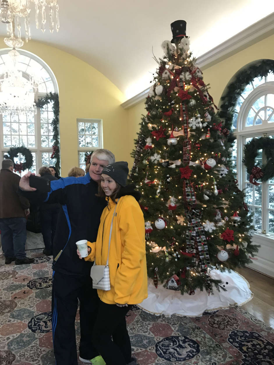 In the conservancy overlooking the gardens, visitors posed for pictures and selfies in front of another tall tree decorated with lights and red and gold ornaments of many shapes. (WTOP/Dick Uliano)