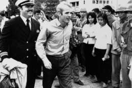 John S. McCain III is escorted by Lt. Cmdr. Jay Coupe Jr., public relations officer, March 14, 1973, to Hanoi's Gia Lam Airport after the POW was released.  (AP Photo/Horst Faas)