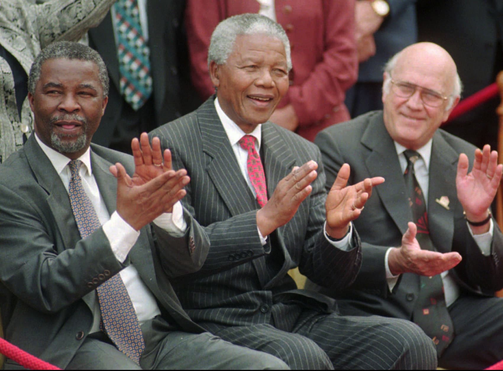 FILE - In this May 8, 1996 file photo, South African President Nelson Mandela, center, applauds along with his two deputy presidents, Thabo Mbeki, left, and F.W. de Klerk, after a new constitution was approved by the Constitutional Assembly in Cape Town, South Africa.   South Africa's president Jacob Zuma says, Thursday, Dec. 5, 2013, that Mandela has died. He was 95.  (AP Photo/Argus, Leon Muller, File)