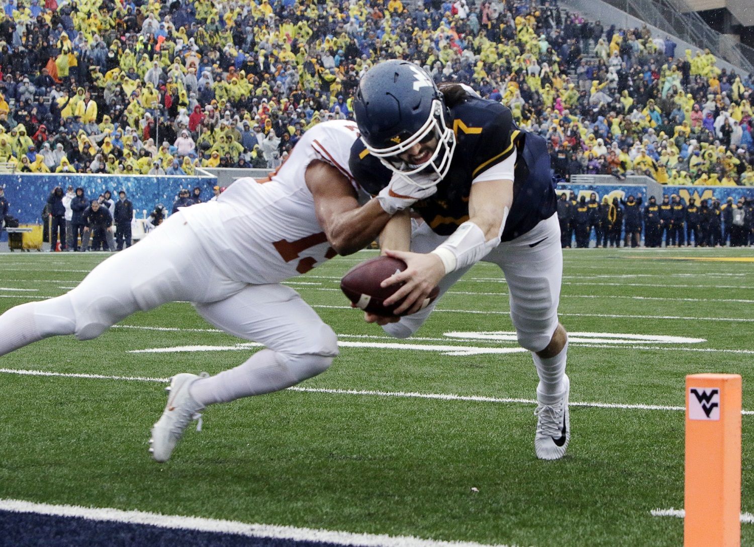 Texas defensive back Brandon Jones (19) tackles West Virginia quarterback Will Grier (7) short of the goal line during the first half of an NCAA college football game, Saturday, Nov. 18, 2017, in Morgantown, W.Va. Grier injured his hand in during the play and left the game. (AP Photo/Raymond Thompson)