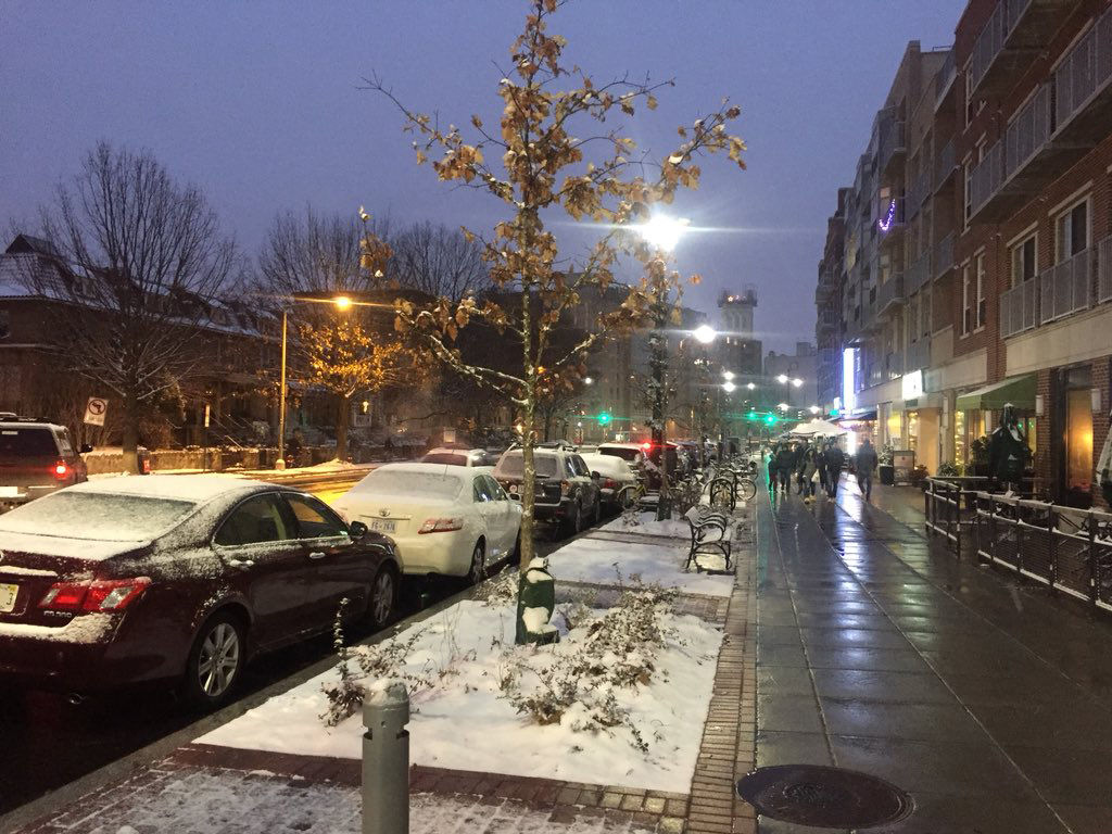 Snow falls on Wisconsin Avenue on Saturday night. A mix of warm temperatures and pretreated roads kept the snow from accumlating on the pavement in most areas. (WTOP/Patrick Roth)