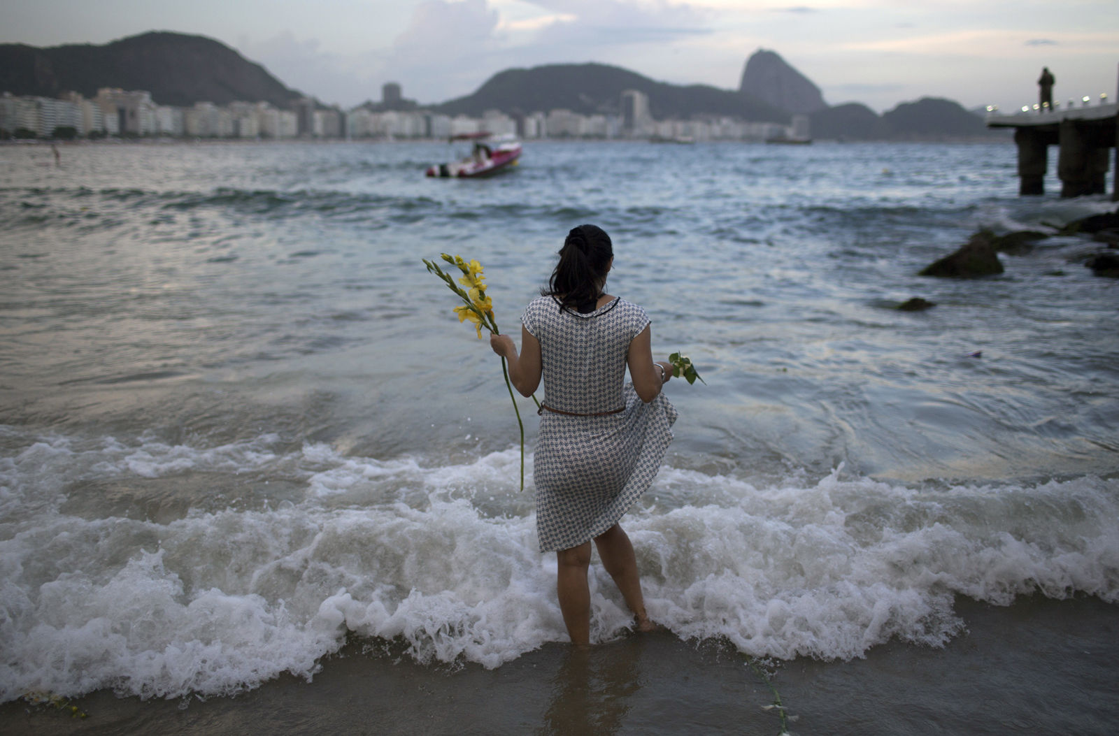 A woman offers flowers to Yemanja, goddess of the sea, for good luck in the coming year during New Year's Eve festivities on Copacabana beach in Rio de Janeiro, Brazil, Saturday, Dec. 31, 2016. The belief in the goddess comes from the African Yoruba religion brought to America by West African slaves. (AP Photo/Leo Correa)
