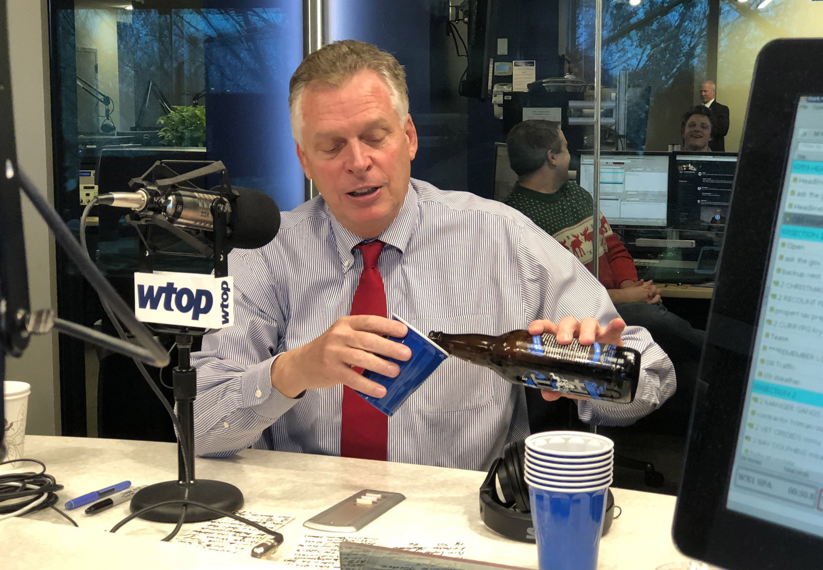 Virginia Gov. Terry McAuliffe pours a beer in the Glass Enclosed Nerve Center on Friday, Dec. 22, 2017, to toast his 38th and final appearance on "Ask the Governor." He picked the ingredients used to make the Give Me Stout or Give me Death, a colaboration among three Virginia breweries: Stone, Hardywood and Ardent. (WTOP/Omama Altaleb)