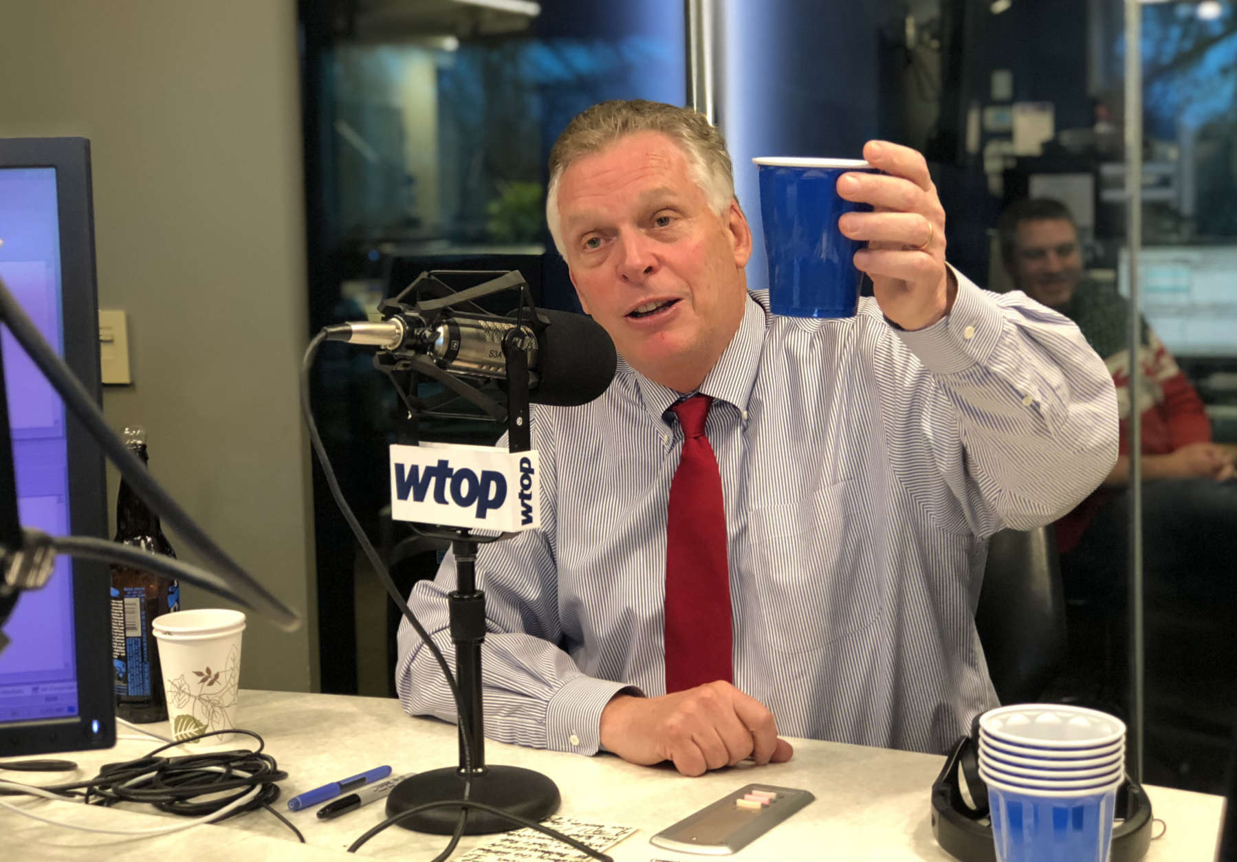 Virginia Gov. Terry McAuliffe raises a glass of beer in the Glass Enclosed Nerve Center during an interview on WTOP on Friday, Dec. 22, 2017. He helped select the ingredients for the stout, a collaboration with Virginia breweries Stone, Hardywood and Ardent. (WTOP/Omama Altaleb)