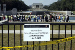 FILE - In this Oct. 2, 2013 file photo, despite signs stating that the national parks are closed, people visit the World War II Memorial in Washington. The federal government shutdown may have seemed like a frustrating squabble in Washington, but it crept into our lives in small, subtle ways _ from missed vegetable inspections to inaccessible federal websites. (AP Photo/Susan Walsh, File)