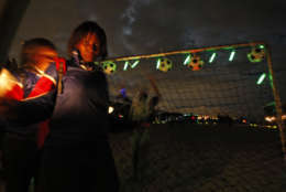 People look on holding  candle lights as other play soccer, at the beach of Muizenberg situated on the outskirts of  Cape Town, South Africa, Saturday, March 27, 2010. People took part in Earth Hour celebration  by taking part in a soccer game with a luminous ball and standing with candle light's. (AP Photo/Schalk van Zuydam)