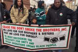 Event-goers hold up a sign at the MLK Peace Walk and Parade. (WTOP/Kristi King)