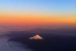 New Zealand's Mount Taranaki has a warm glow lighting the snow peak as an ash cloud from a Chilean volcano drifts across the Pacific, Sunday, June 12, 2011. Most airlines grounded more flights to and from southern Australia and New Zealand on Monday morning after an ash cloud from the Cordon Caulle volcano in southern Chile expanded overnight. (AP Photo/David Frampton) NEW ZEALAND OUT, EDITORIAL USE ONLY
