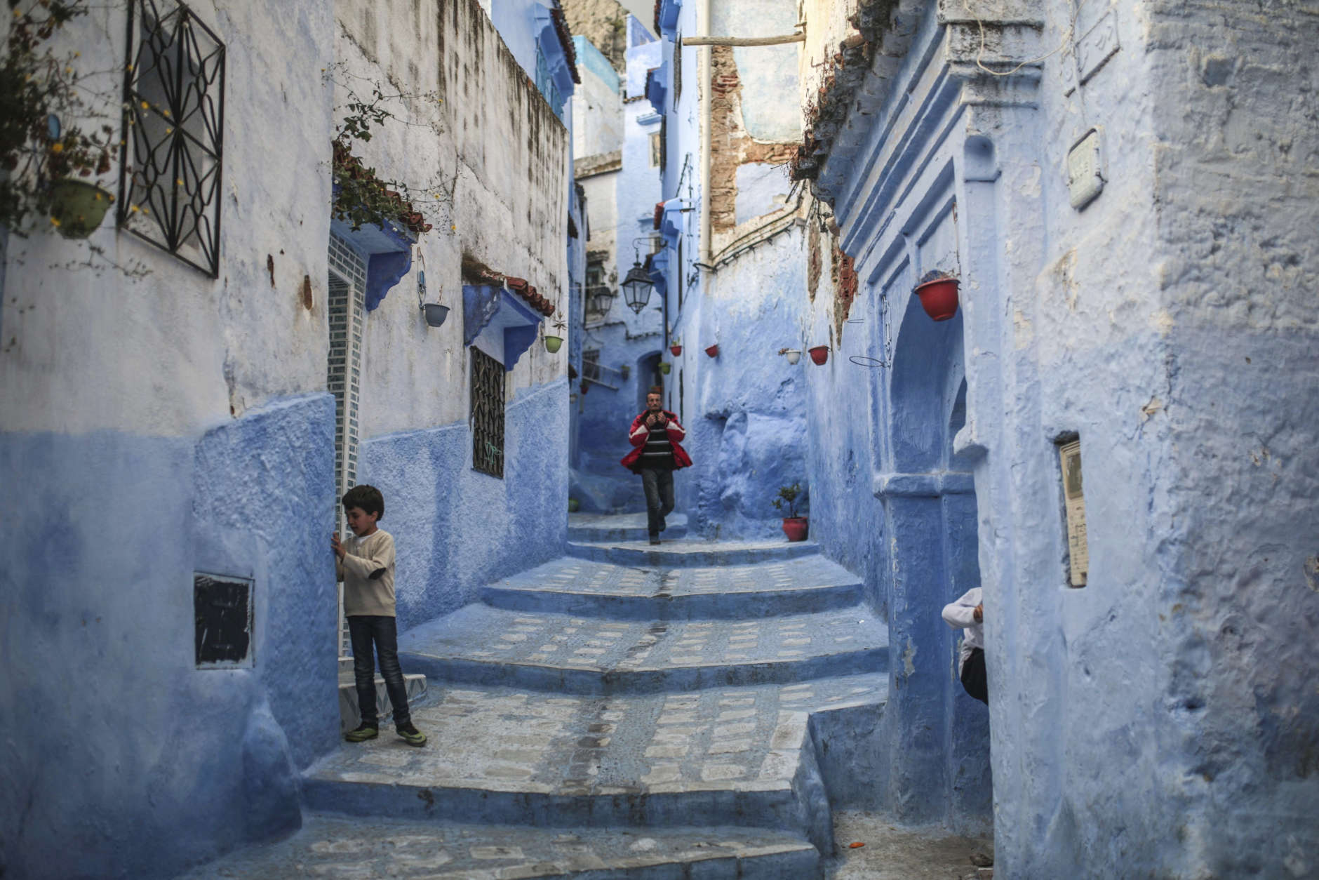 A boy plays outside his house while a man walks down an alleyway in the Medina of Chefchaouen, a picturesque town well-known for its blue painted houses and alleyways, in northern Morocco, Saturday, April 29, 2017. (AP Photo/Mosa'ab Elshamy)