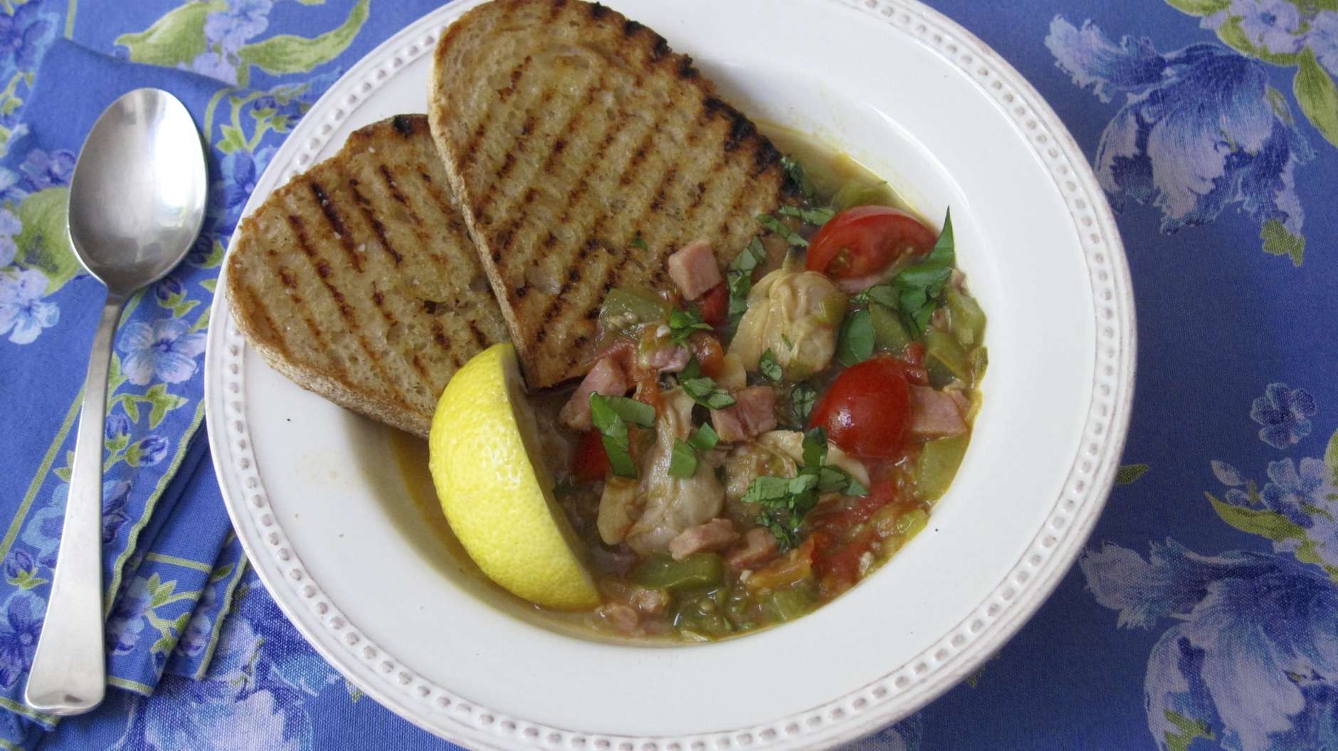Thie June 20, 2017 photo shows a clam, tomato and bacon stew with grilled garlic bread in New York. This dish is from a recipe by Sara Moulton. (Sara Moulton via AP)