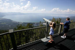In this photo taken Tuesday, Aug. 8, 2017, Lilyana Allen, of Guam, uses a telescope to view Lake Tahoe from an observation platform at the Heavenly Mountain Resort during a family visit to South Lake Tahoe, Calif. Lake Tahoe's known for summer and winter fun, but there's a third side to Tahoe: fall, when crowds thin out, rates are cheaper, weather's mild and there's even some leaf-peeping. (AP Photo/Rich Pedroncelli)