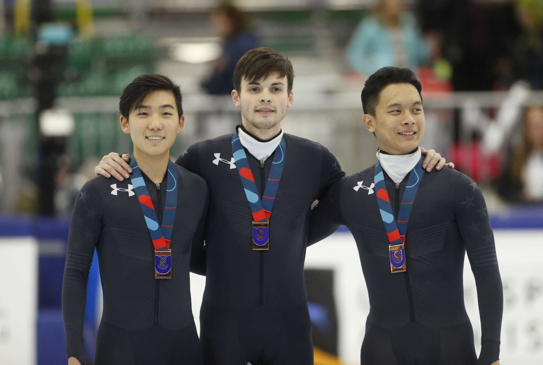 First place finisher John-Henry Krueger, center, stands with third place finisher, left, Thomas Insuk Hong and second place finisher Aaron Tran, right, following the men's 500-meter during the U.S. Olympic short track speedskating trials Saturday, Dec. 16, 2017, in Kearns, Utah. (AP Photo/Rick Bowmer)