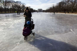 A visitors push her stroller on the frozen Reflecting Pool at the National Mall, Sunday, Jan. 7, 2018, in Washington. The bitter cold that followed a massive East Coast snowstorm should begin to lessen as temperatures inch up and climb past freezing next week. ( AP Photo/Jose Luis Magana)