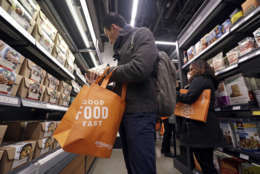 Customer Paul Fan shops at an Amazon Go store, Monday, Jan. 22, 2018, in Seattle. The store on the bottom floor of the company's Seattle headquarters allows shoppers to scan their smartphone with the Amazon Go app at a turnstile, pick out the items they want and leave. The online retail giant can tell what people have purchased and automatically charges their Amazon account. (AP Photo/Elaine Thompson)