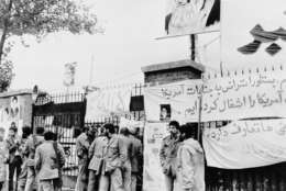 FILE - In this Nov. 6, 1979 file photo, students stand guard before the entrance of the United States Embassy where staff is being held hostage in Tehran, as a portrait of Ayatollah Khomeini is on display. The Obama administration asked a federal judge Tuesday, April 21, 2009 to throw out a lawsuit against Iran filed by Americans held hostage at the embassy in Tehran 30 years ago. In court papers filed Tuesday night, the Justice Department argued that the agreement to release the hostages precluded lawsuits against Iran. (AP Photo/File)