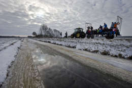 Participants of the Five Lakes Skating Tour are being transported on a tractor to avoid a stretch of bad ice in Wanneperveen, near Giethoorn, northern Netherlands, Thursday Jan. 24, 2013. Some 15,000 skating enthusiasts participated in the first tour on natural ice, but a stretch of rapidly deteriorating ice  in Wanneperveen forced organizers to call off the tour after a few hours. Dutch police later stopped people from reaching the area. (AP Photo/Peter Dejong)