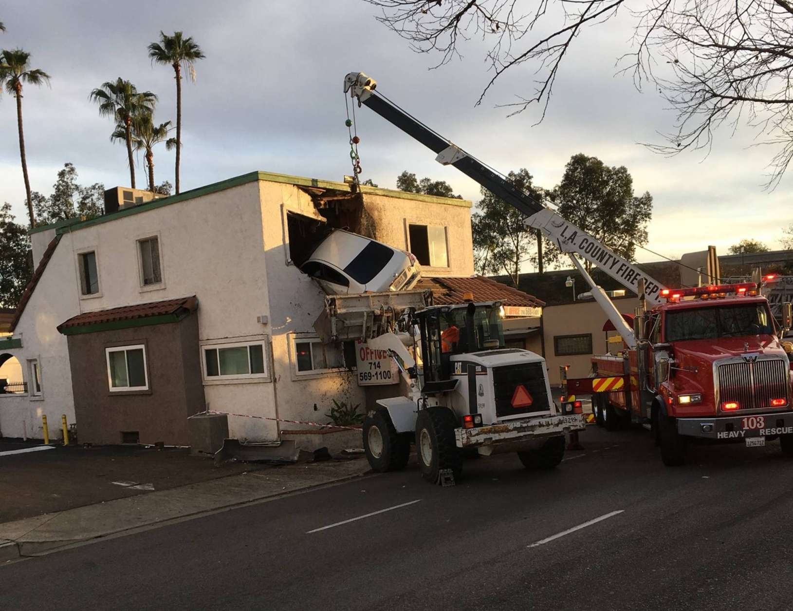 In this Sunday, Jan. 14, 2018, photo provided by Orange County Fire Authorit, a vehicle that crashed into a building hangs from a second story window in Santa Ana, Calif. Members from Orange County Fire Authority and Los Angeles County Urban Search &amp; Rescue rescued two people, who escaped serious injuries when the car they were in went airborne and slammed into the second floor of a dental office in Southern California. Authorities say the Nissan Altima hit a center divider early Sunday, soared into the air and plowed into the top floor of the two-story structure. (Capt. Stephen Horner /Orange County Fire Authority via AP)