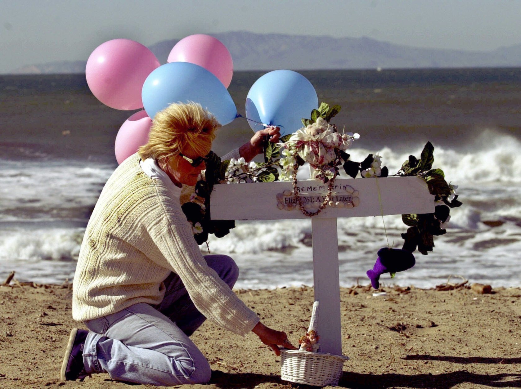 Nancy Fry of Oxnard Calif., arranges balloons and a basket at a  memorial on Silver Strand Beach in Oxnard, Calif., Tuesday, Jan. 30, 2001, created in memory of the 88 victims of the Jan. 31, 2000 crash of Alaska Airlines Flight 261.  The twin-engine MD-83 was on its way to San Francisco and then Seattle when it started pitching, then spiraled from nearly 18,000 feet into the Pacific Ocean.  (AP Photo/Nick Ut)