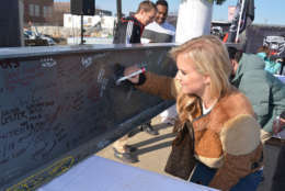 D.C. United fans on Friday sign the topping-off beam at the Audi Field construction site. (Juan Herrera/Capital News Service)
