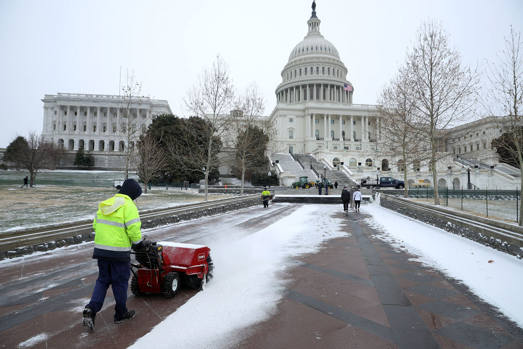 WASHINGTON, DC - JANUARY 04:  Architect of the Capitol Gardener Mike Naas sweeps snow in front of the U.S. Capitol January 4, 2018 in Washington, United States. A large winter storm system dropped less than an inch of snow in Washington and is covering the East Coast with high winds and frigid temperatures.  (Photo by Chip Somodevilla/Getty Images)