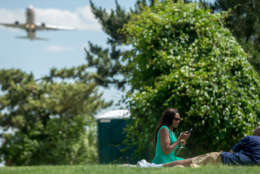 A plane takes off from Washington's Ronald Reagan National Airport as Marcel Clark of Washington, right, and Rosemary Loza of Rockville, Md. picnic at Gravelly Point Park in Arlington, Va., Wednesday, June 8, 2016. (AP Photo/Andrew Harnik)