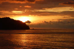 Gorgeous orange tropical Pacific sunset in Sayulita, Mexico with paddle-boarder admiring the beauty.
