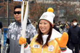 Lee waves while carrying the torch during the Olympic torch relay in Seoul, South Korea. (WTOP/Suann Lee)