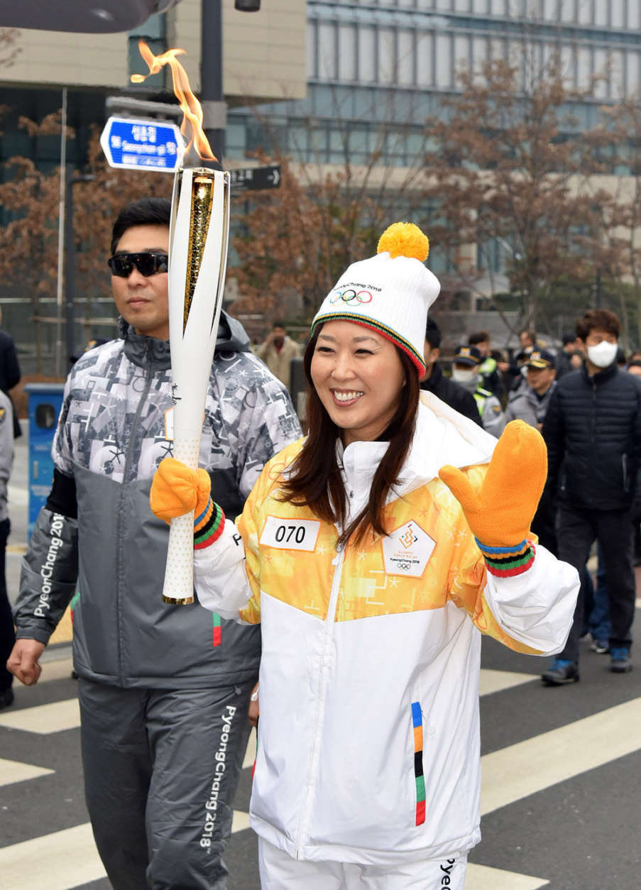 Lee waves while carrying the torch during the Olympic torch relay in Seoul, South Korea. (WTOP/Suann Lee)