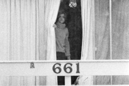 An unidentified woman peers through drapes on the 2nd story balcony of the Chi Omega sorority house at Florida State University in Tallahassee, Fla., Jan. 15, 1978. Two sorority sisters, Margaret Bowman and Lisa Levy, were brutally beaten to death with the assailant leaving 3 others injured early Sunday morning. (AP Photo/Mark Foley)