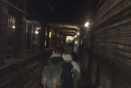 Photo shows a dark Metro tunnel and passengers in it