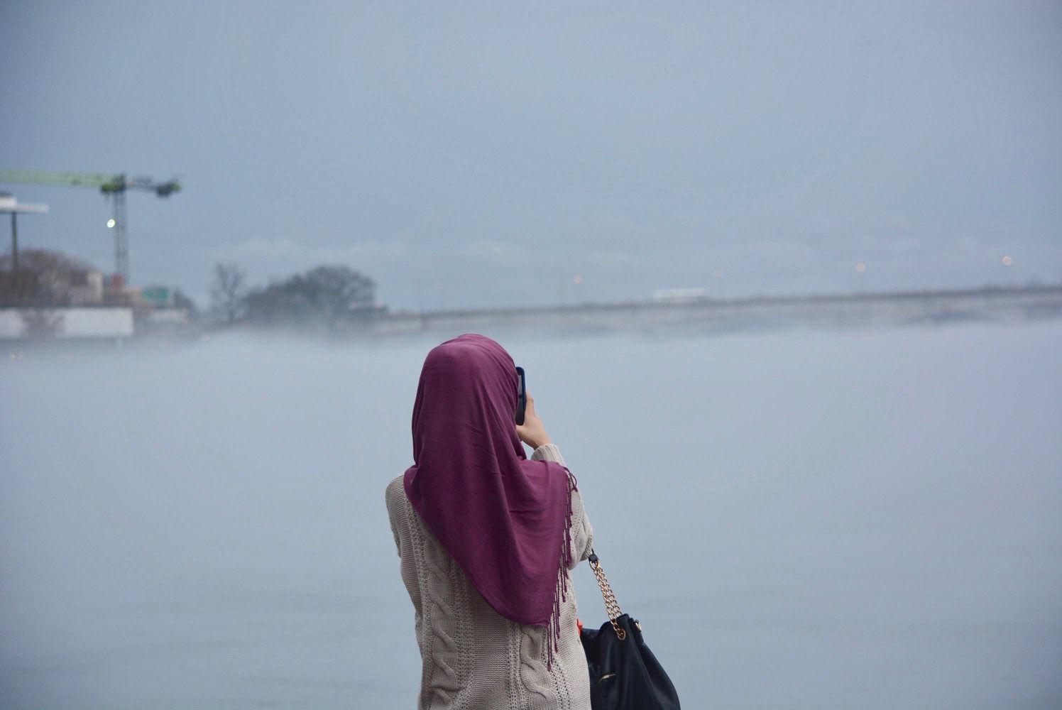 A woman snaps a photo of the deep blanket of fog that rose off the cold waters of the Potomac River on Friday, Jan. 12, 2018 amid a mid-January warmup. (WTOP/Dave Dildine)