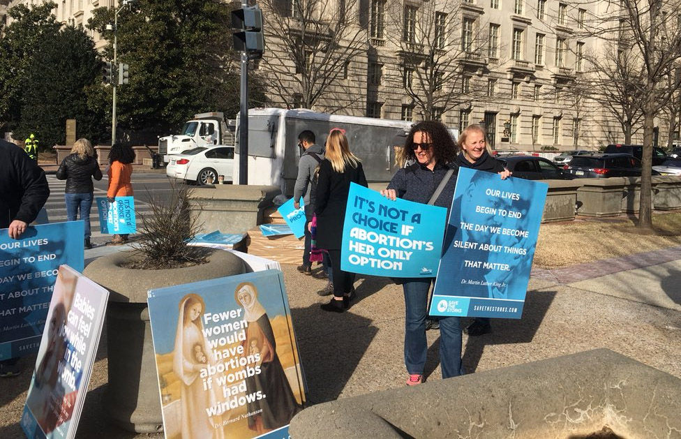 Volunteers pass out signs to abortion rights opponents near the National Mall on Jan. 19, 2018. More than 50,000 people were expected to take part in the annula March for Life, marking 45 years since the landmark Supreme Court decision Roe v. Wade legalized abortion. (WTOP/Mike Murillo)