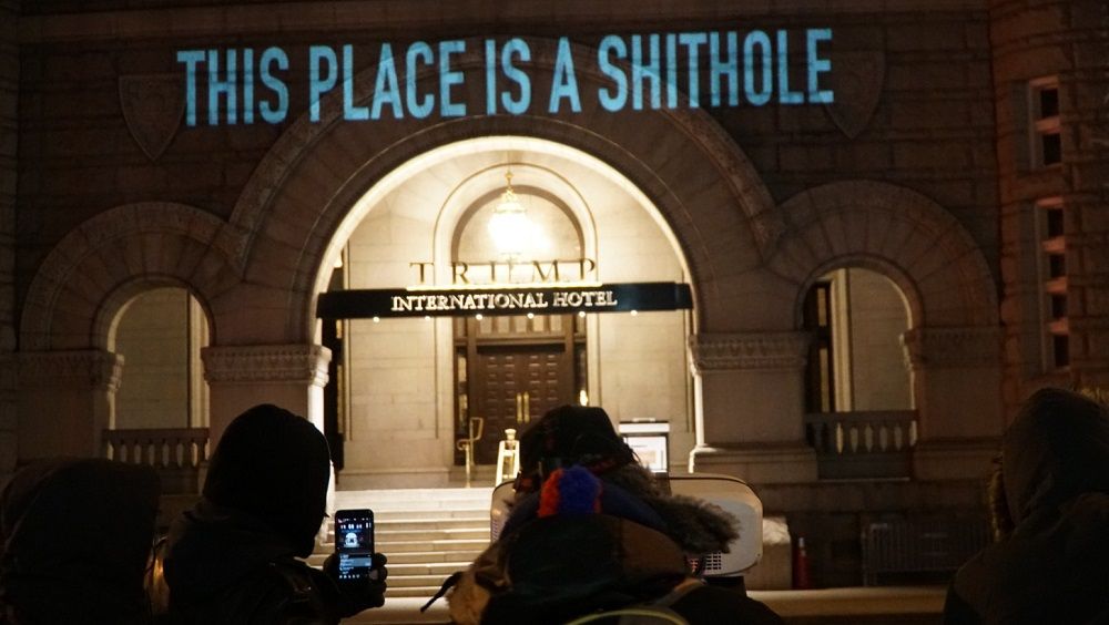 People gather to photograph the projections on Trump Hotel in D.C. on Saturday. The projections reference President Trump's recent comments on immigrants from Haiti and African countries. (Courtesy Sorane Yamahira/Bell Visuals)