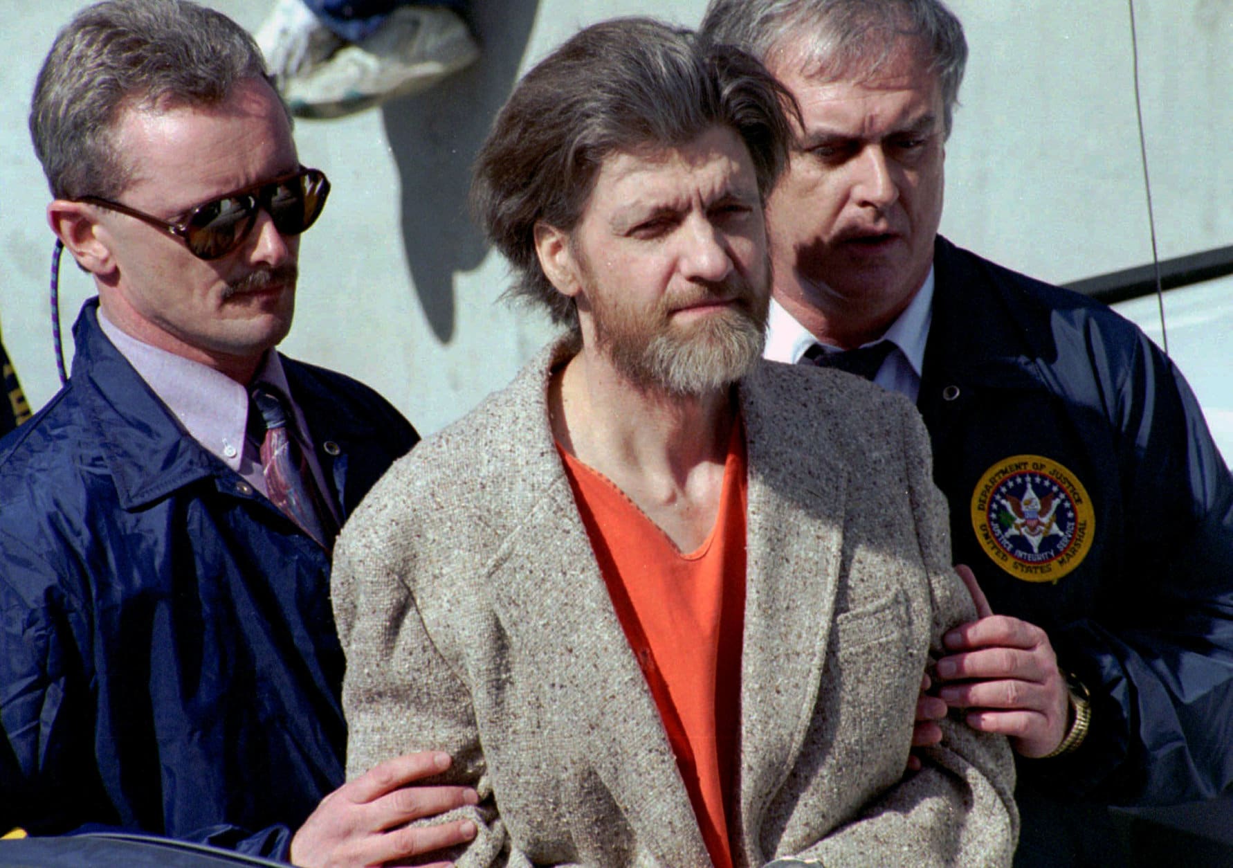 FILE - In this April 4, 1996 file photo, Ted Kaczynski, better known as the Unabomber, is flanked by federal agents as he is led to a car from the federal courthouse in Helena, Mont. Twenty years after the arrest of Kaczynski, some Lincoln residents remember him as an odd recluse who ate rabbits and lived without electricity, while others say he had a funny, personable side. Kaczynski is serving a life sentence in a federal prison in Florence, Colorado, for a series of bombings, most through the mail, that killed three people and injured 23 others over 17 years. (AP Photo/John Youngbear, File)