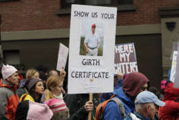 A marcher carries a sign that reads "Show us your girth certificate" and a picture of President Donald Trump during a Women's March, Saturday, Jan. 20, 2018 in Seattle. The march was one of dozens planned across the U.S. over the weekend. (AP Photo/Ted S. Warren)