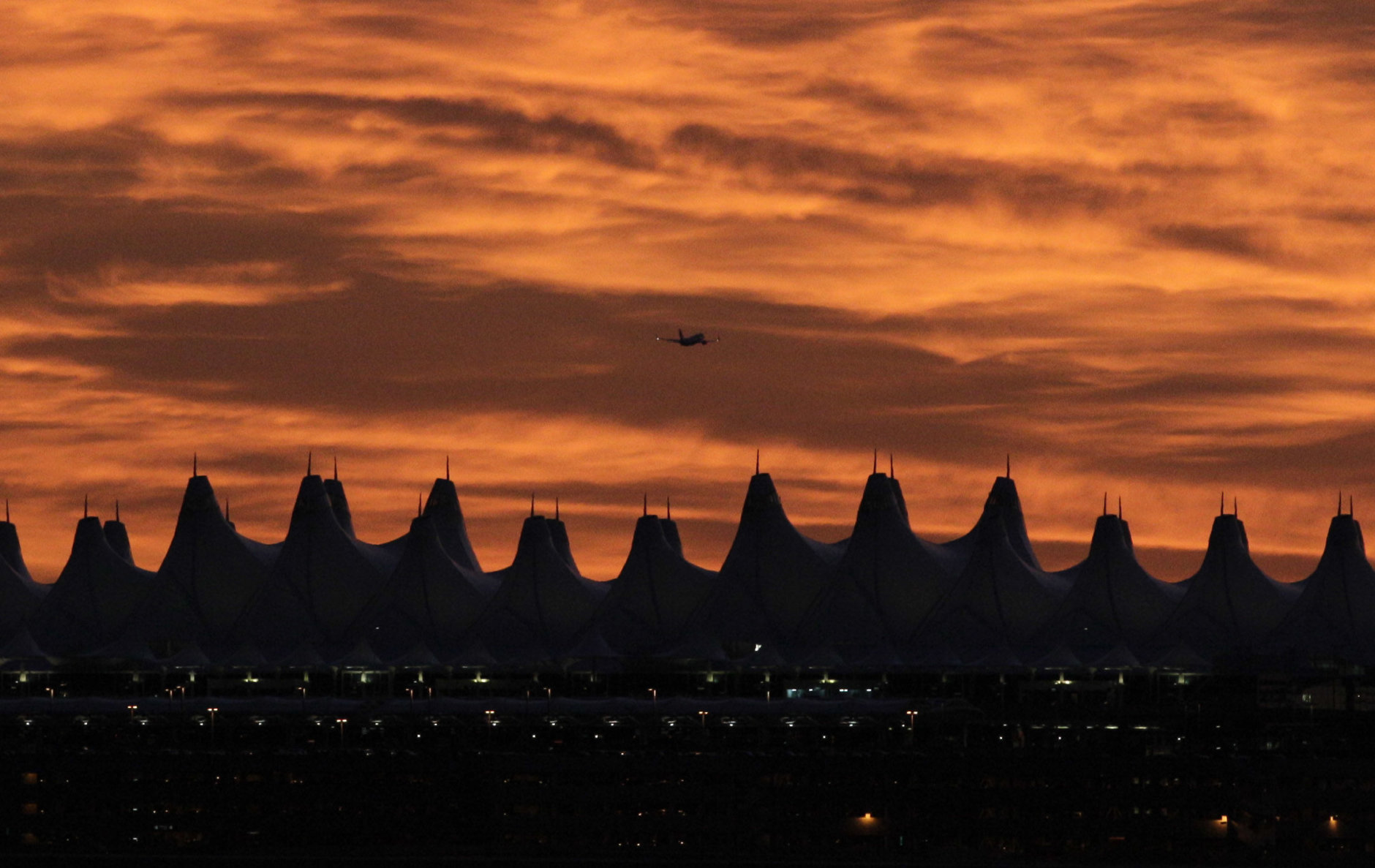 A plane takes off from Denver International Airport early morning as clouds reflect the colors of the sunrise in Denver, Sunday, Sept. 12, 2010. (AP Photo/Jae C. Hong)
