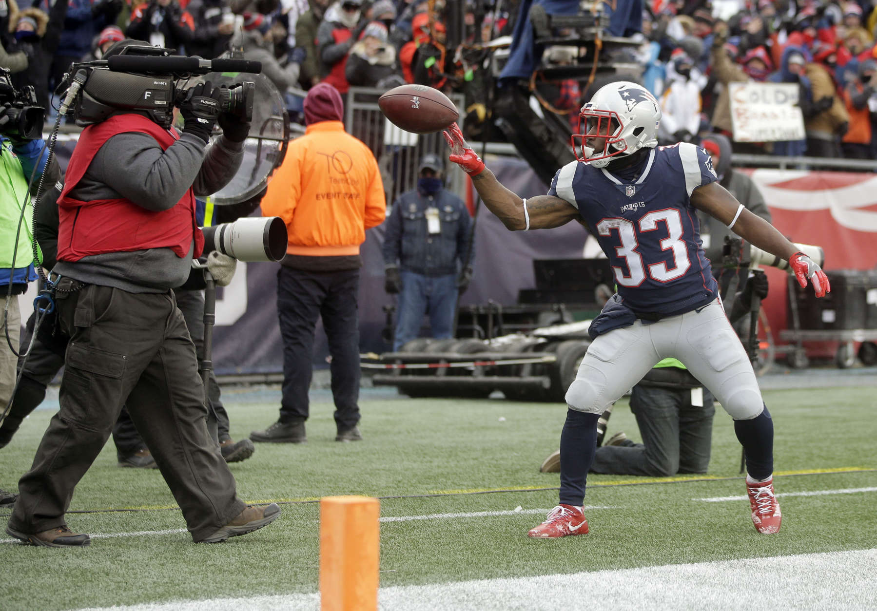 New England Patriots running back Dion Lewis (33) tosses the football at a network sideline camera after scoring a touchdown against the New York Jets during the first half of an NFL football game, Sunday, Dec. 31, 2017, in Foxborough, Mass. (AP Photo/Steven Senne)