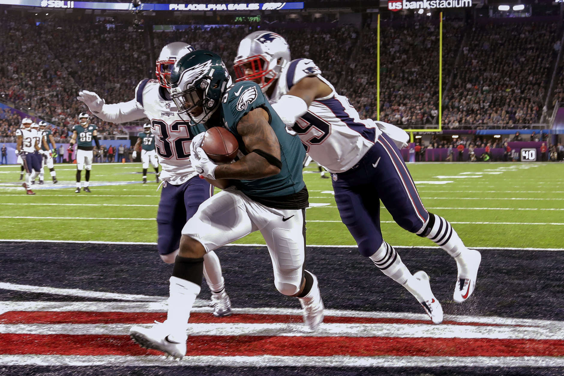 Philadelphia Eagles running back Corey Clement (30) scores a touchdown, as New England Patriots cornerback Johnson Bademosi (29) and free safety Devin McCourty (32) are late with the tackle, during the second half of the NFL Super Bowl 52 football game, Sunday, Feb. 4, 2018, in Minneapolis. (AP Photo/Chris O'Meara)