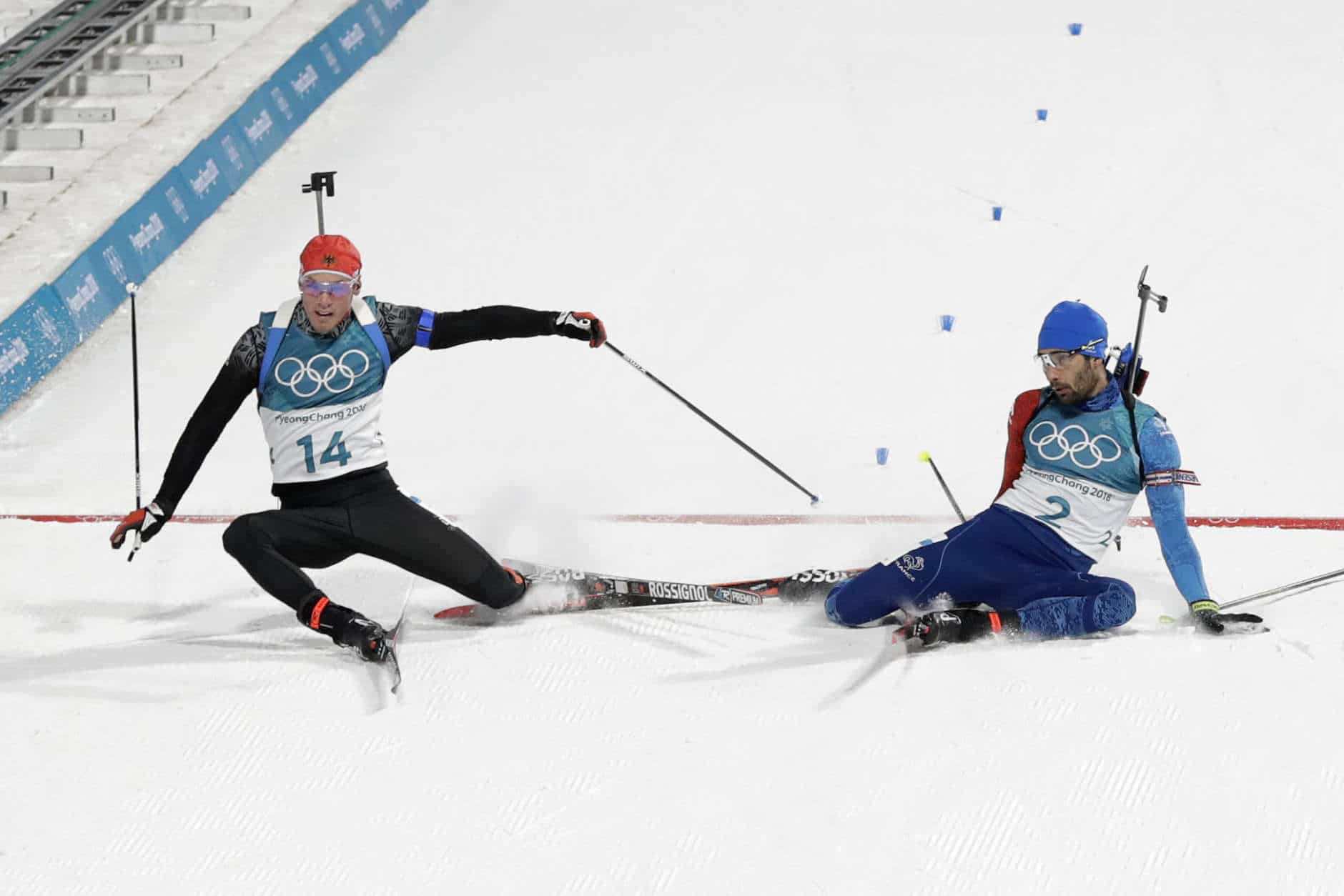 Simon Schempp, of Germany, left, and Martin Fourcade, of France, right, fall as they cross the finish line during the men's 15-kilometer mass start biathlon at the 2018 Winter Olympics in Pyeongchang, South Korea, Sunday, Feb. 18, 2018. Fourcade won the gold medal defeating Schempp in a photo finish. (AP Photo/Andrew Medichini)