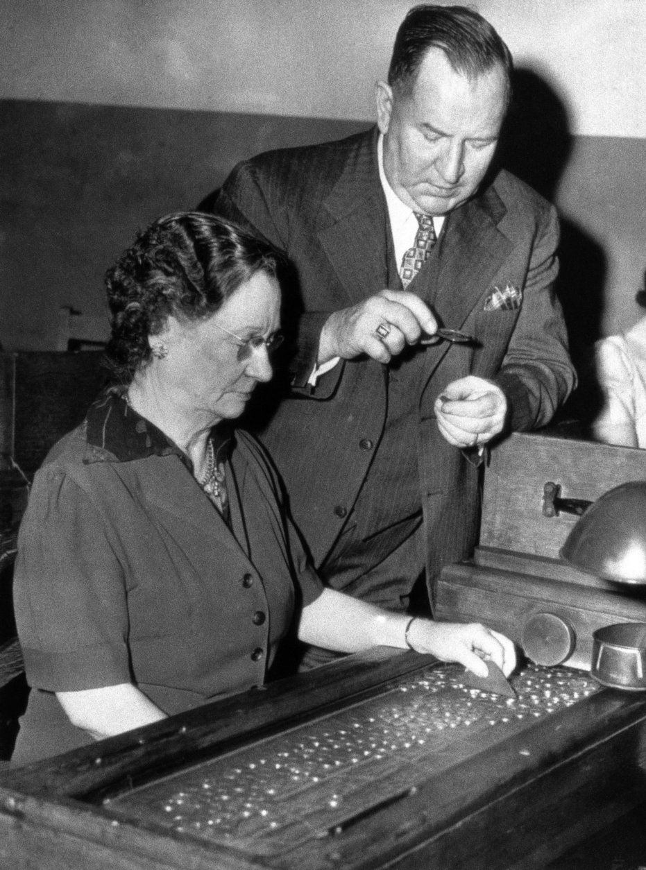 Odwin Dressel, superintendent of the Philadelpia Mint, and Mrs. Martha Richardson, an employee, inspect new type zinc and steel pennies rolling from the stamping marchines at the mint on March 3, 1943. The coins look much like dimes. (AP Photo)