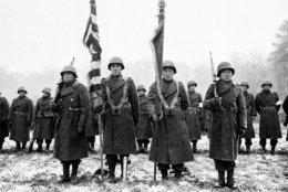 Two color guards and color bearers of the Japanese-American 442nd Combat team stand at attention while their citations are read somewhere in France during World War II on Nov. 12, 1944 .  They  are standing on the ground where many of their comrades fell.  (AP Photo/U.S. Army Signal Corps)
