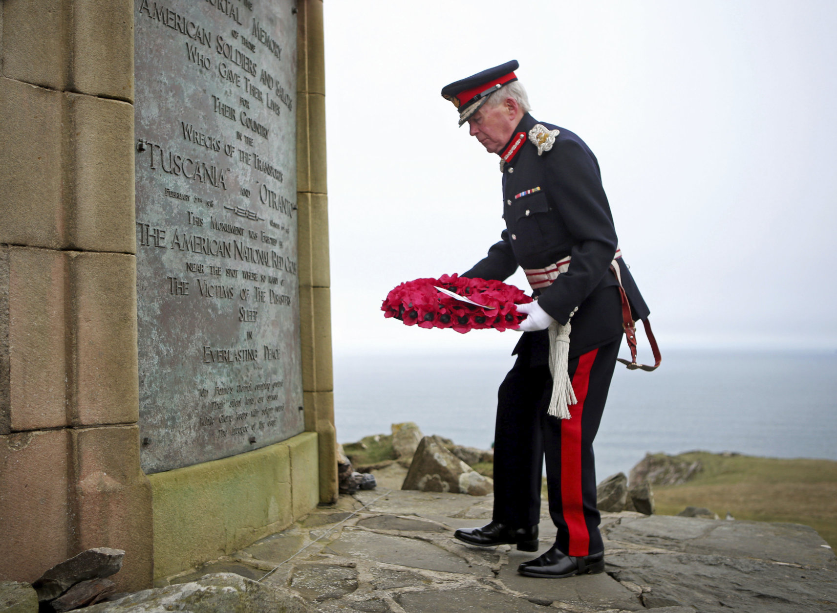 Lord Lieutenant of Argyll and Bute, Patrick Stewart, lays a wreath during a service at the American Moment at the Mull of Oa on Islay, Scotland, Friday May 4, 2018. Relatives of U.S. soldiers who died in two sea disasters off the coast of Scotland during World War I have traveled to the island of Islay for a service honoring those who were lost and the local people who rescued the survivors. The ceremony commemorates the sinking of two troop carriers, the SS Tuscania in February 1918 and the HMS Otranto eight months later, where some 700 U.S. servicemen and British crew members lost their lives. (Jane Barlow/PA via AP)