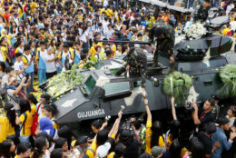 Students hand flowers to soldiers during the 30th anniversary celebration of the "People Power Revolution" that toppled the 20-year-rule of the late strongman Ferdinand Marcos and helped install Corazon "Cory" Aquino to the presidency Thursday, Feb. 25, 2016 at suburban Quezon city northeast of Manila, Philippines. The four-day People Power saw hundreds of thousands of Filipinos trooping to EDSA Avenue fronting two military camps to lend support to mutinous soldiers who broke away from Marcos.(AP Photo/Bullit Marquez)