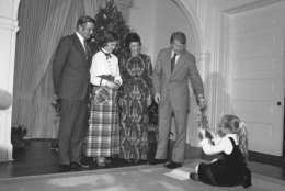 President Jimmy Carter reaches for an ornament from daughter Amy as he poses with Vice President Walter Mondale, left, First Lady Rosalynn Carter, second from left, and Joan Mondale in front of the Mondales Christmas tree at the Vice Presidents residence in Washington on Sunday, Dec. 18, 1977. The Carters had dinner with the Vice  President and his wife. (AP Photo)