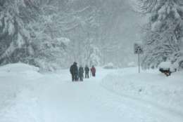 A family walks down a snow-covered street during the February 2010 storm. (WTOP/Dave Dildine)