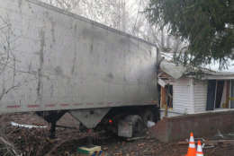A large truck shown crashed through the side wall of a home.