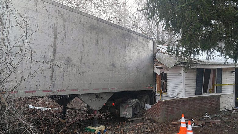 A large truck shown crashed through the side wall of a home.