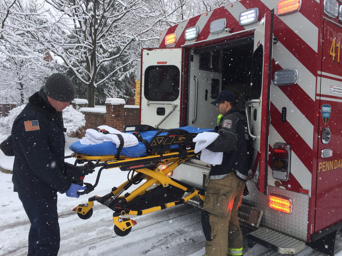 Alexandria Firefighters and medics assist a young woman who fell down in the snow. (WTOP/Kristi King)